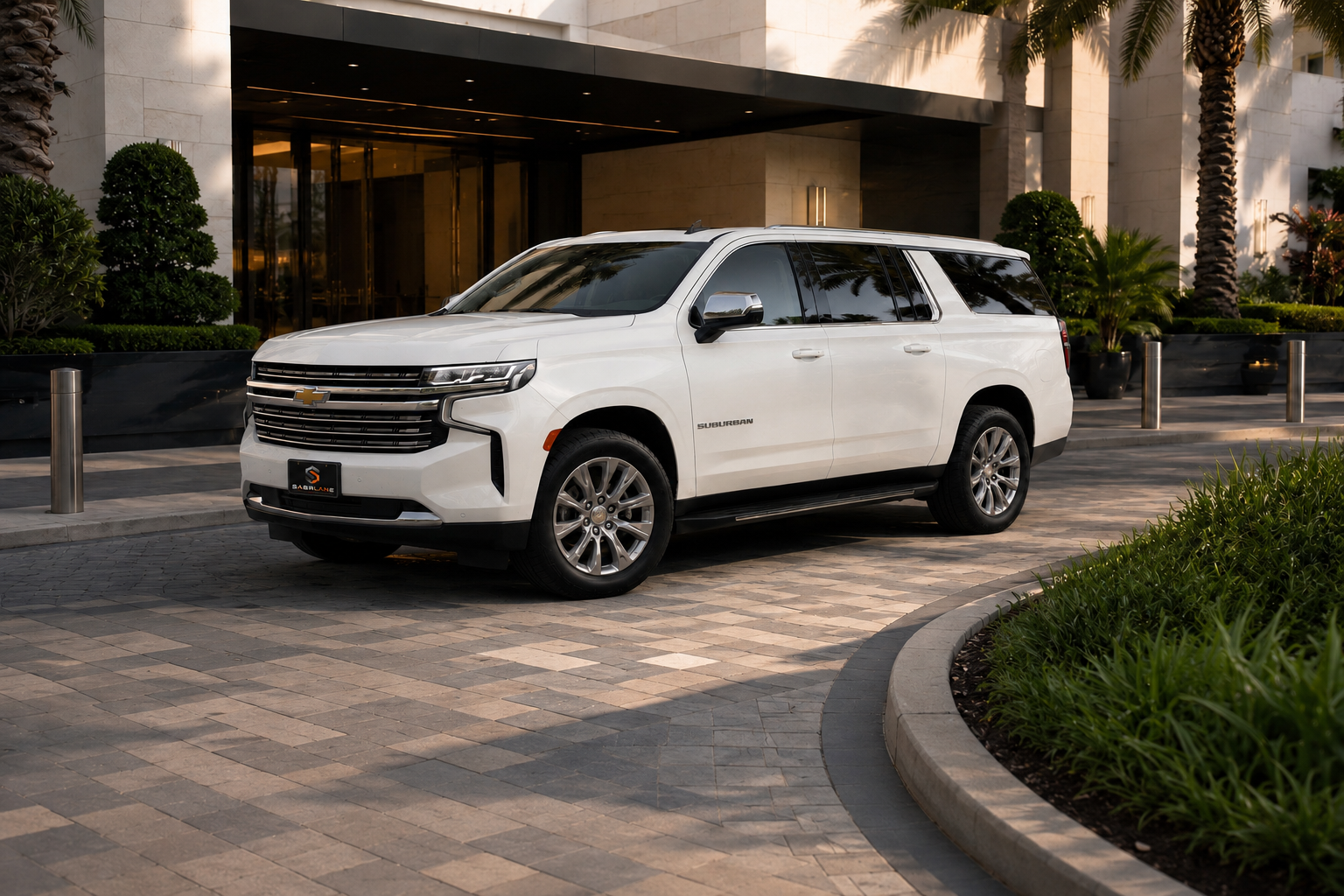 White Chevrolet Suburban Premier at a modern hotel entrance